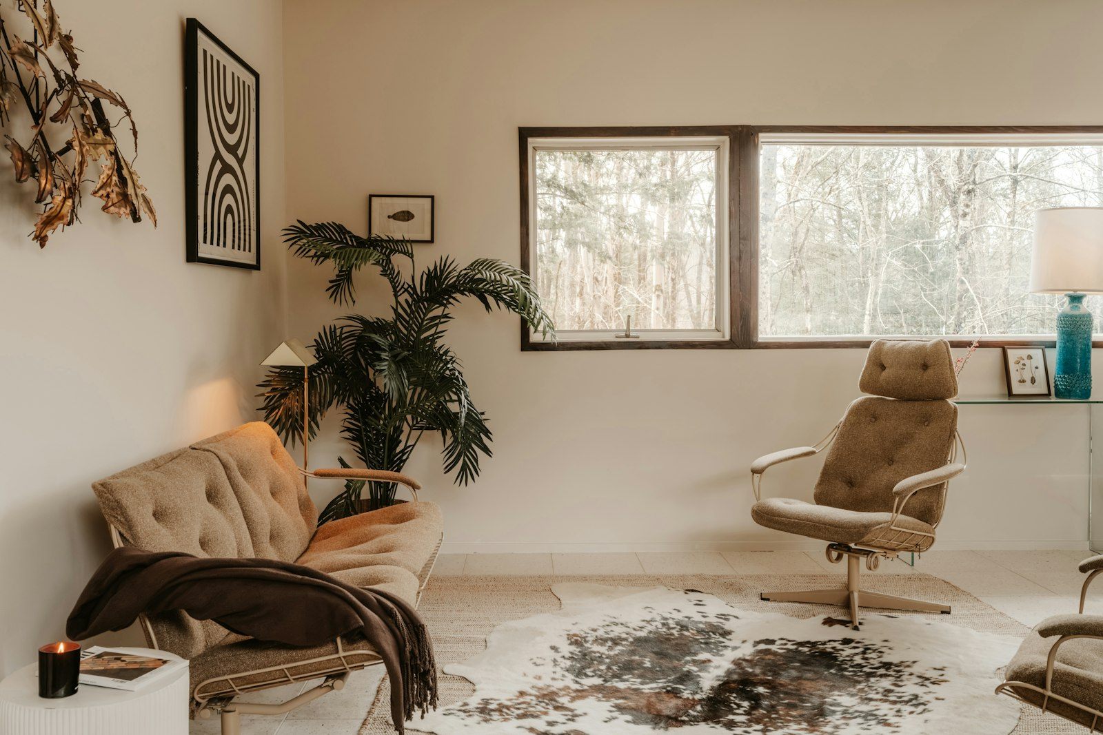 Salon lumineux avec fauteuils vintage beiges, plantes et matières naturelles.